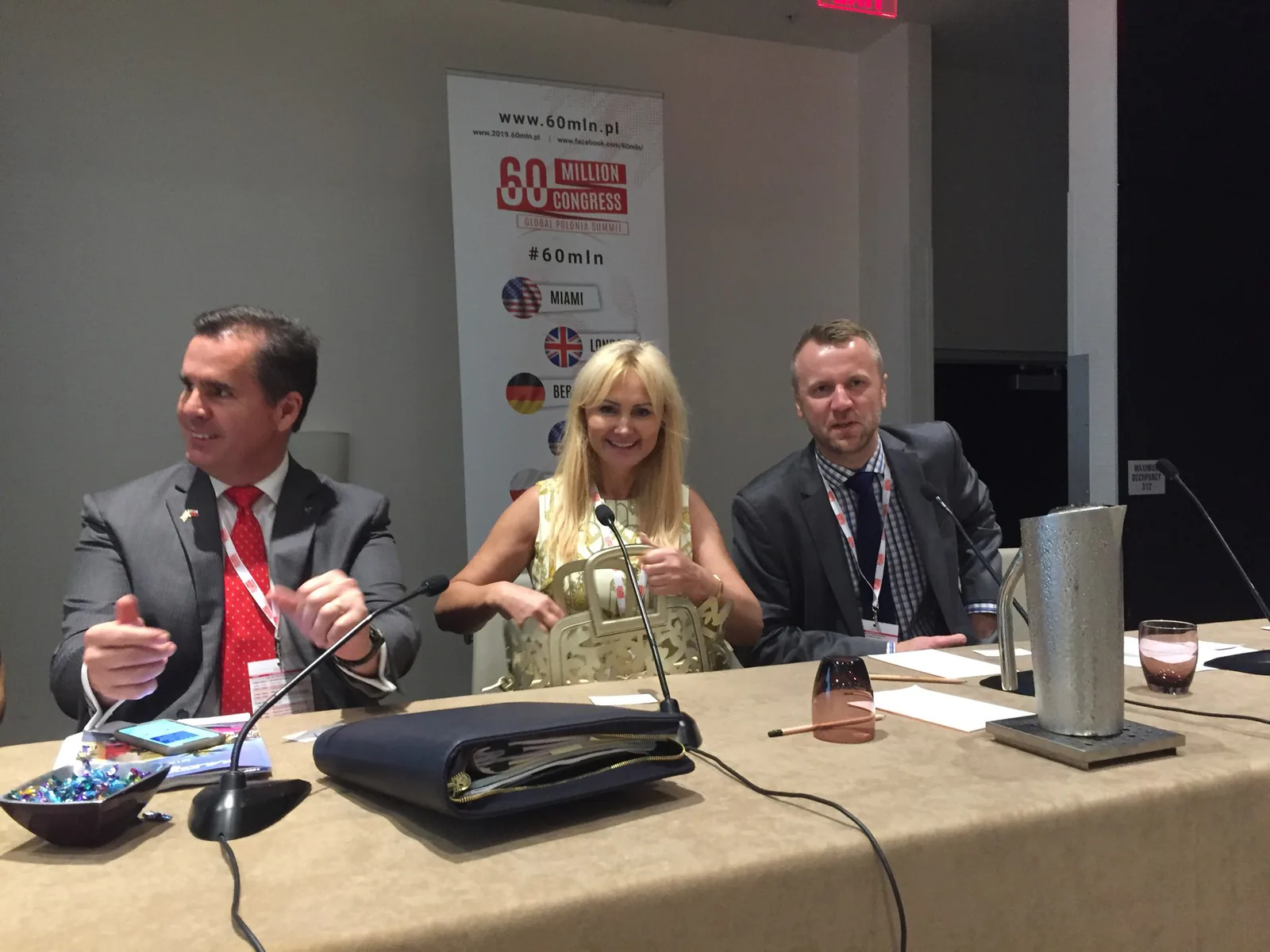 Three panelists seated at a table with microphones in front of a 60 Million Congress Global Polonia Summit banner in Miami, 2019