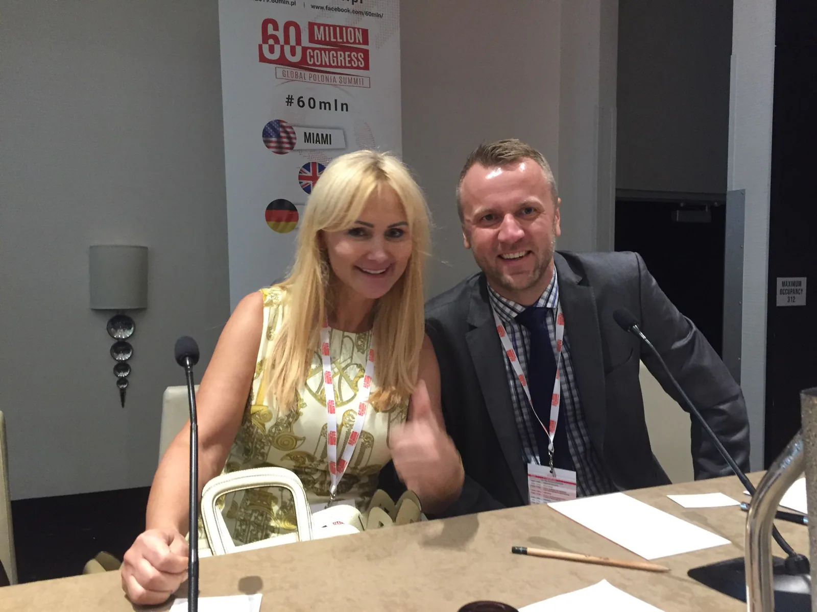 Two smiling panelists at the speakers' table in front of the 60 Million Congress Global Polonia Summit banner in Miami, 2019