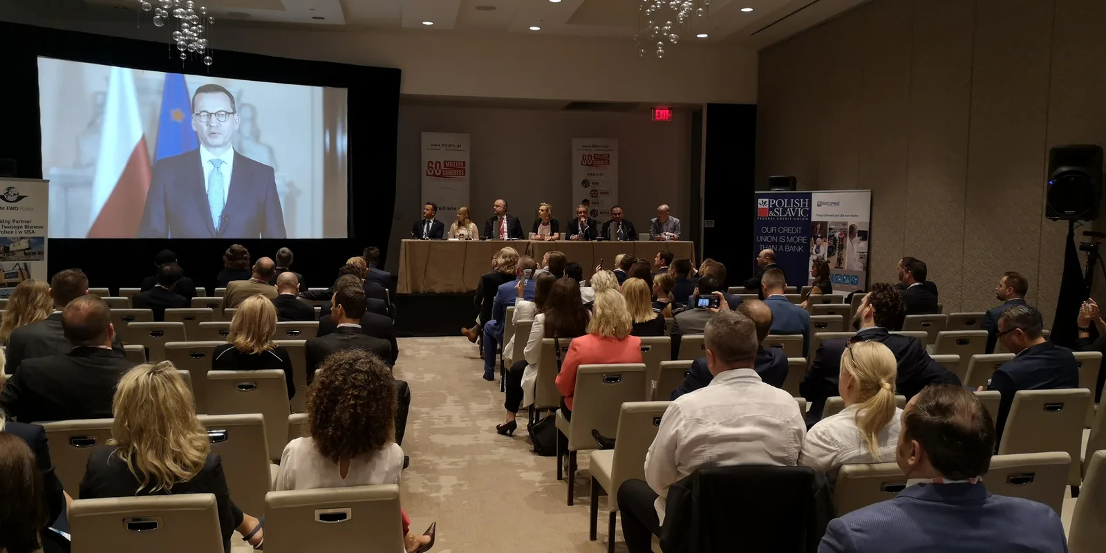 Audience in a hotel conference hall watching a video address in front of Polish and EU flags at the 60 Million Congress in Miami