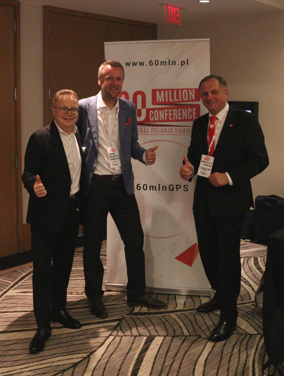 Tomasz Popławski of Ingressus, center, giving a thumbs up with two participants beside a 60 Million Conference banner