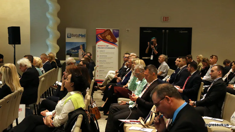 Congress audience in the hotel ballroom, with BetaMed and Benefits of Polish Citizenship roll-up banners in the background