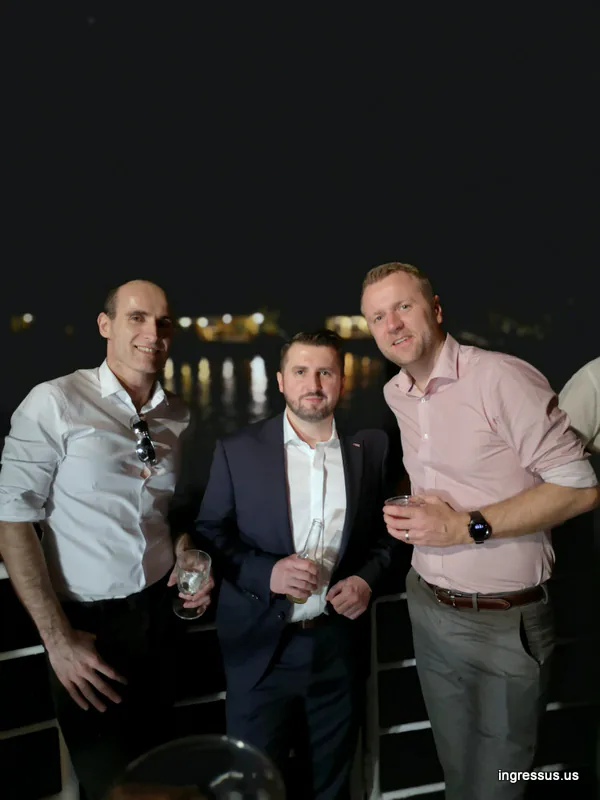 Three congress participants with drinks on the deck of a boat at night during the evening cruise