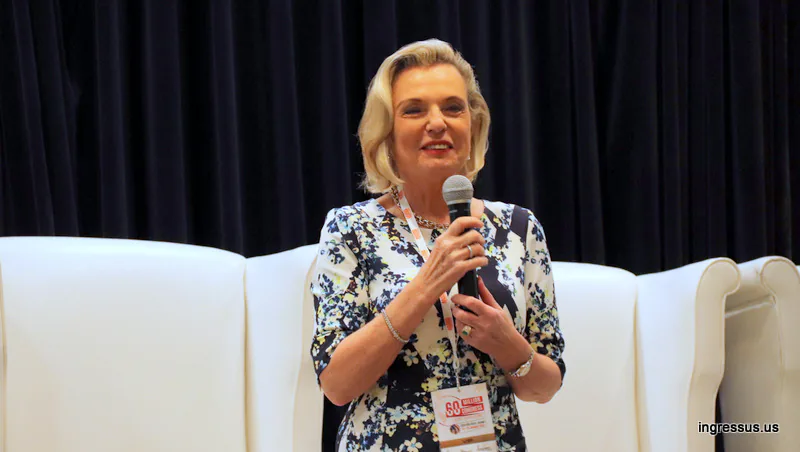 Speaker wearing a 60 Million Congress badge smiling while she addresses the audience with a microphone