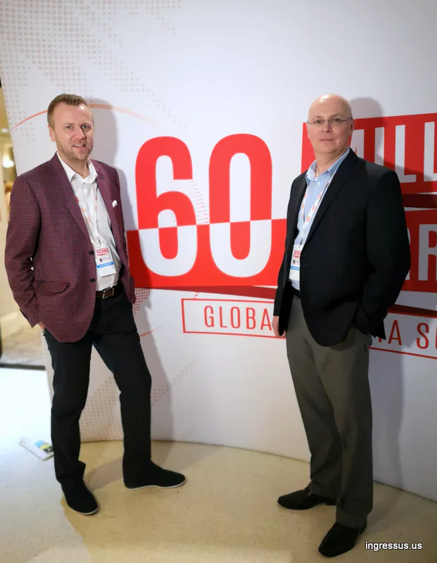 Two congress participants with badges standing in front of the 60 Million Congress Global Polonia Summit backdrop