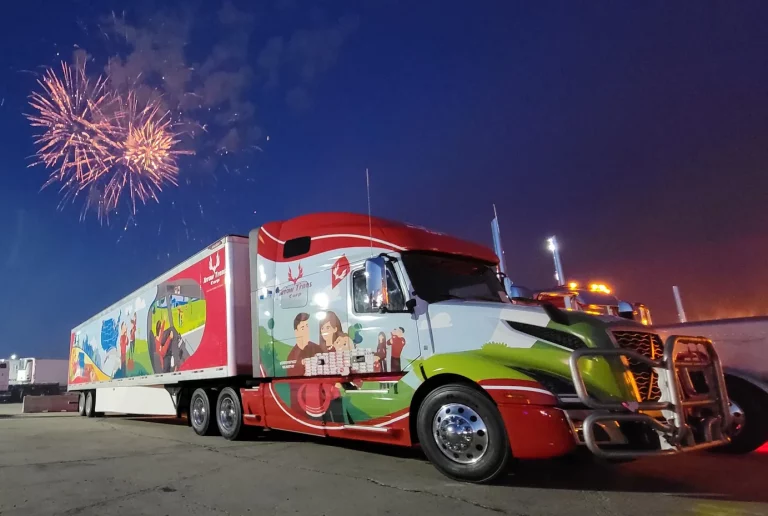 Arrow Trans Corp semi-truck with a custom illustrated wrap on the cab and trailer, parked at night under fireworks