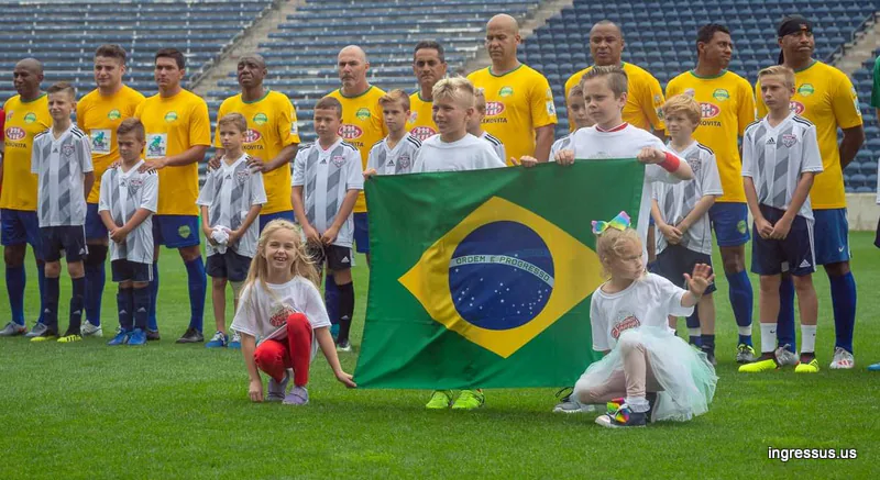 Brazil Legends players lined up with young player escorts holding a Brazil flag before the match at SeatGeek Stadium