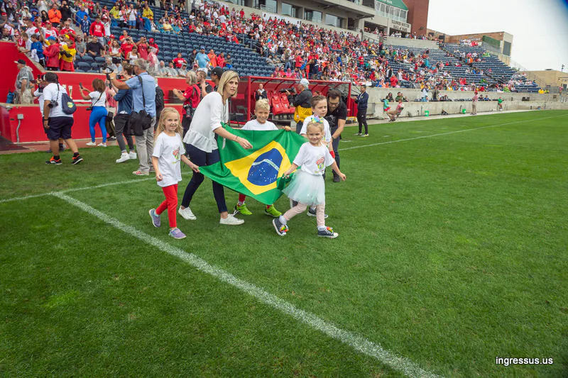 Woman and children carrying a Brazil flag onto the pitch at SeatGeek Stadium before the Soccer Legends Cup match