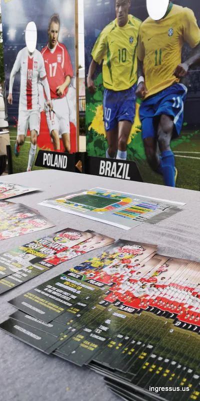 Soccer Legends Cup flyers and a stadium seating chart on a table in front of Poland and Brazil photo boards