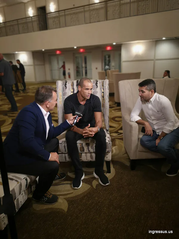 Interviewer with a Canal+ microphone talking with a guest in an armchair at the Soccer Legends Gala