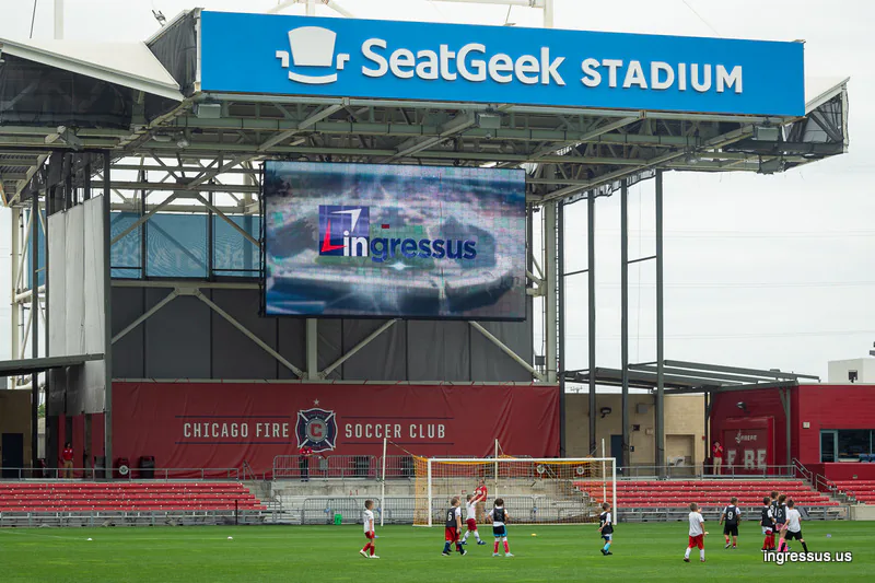 SeatGeek Stadium video board showing the Ingressus logo above the Chicago Fire Soccer Club stand during a youth game