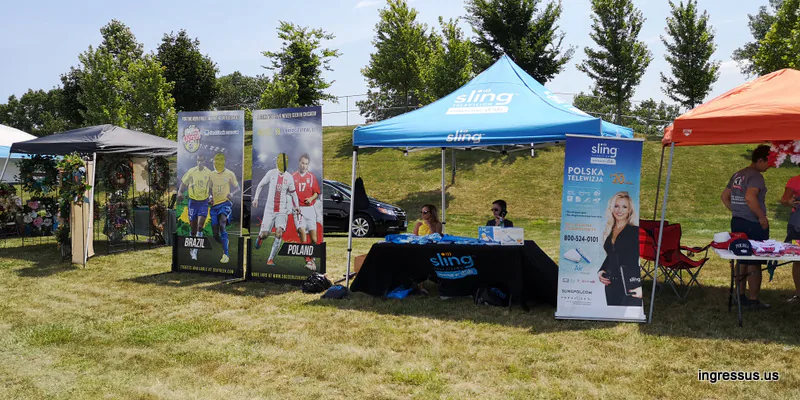 Soccer Legends Cup promo stand at a summer picnic with Brazil and Poland photo boards next to a Sling TV tent