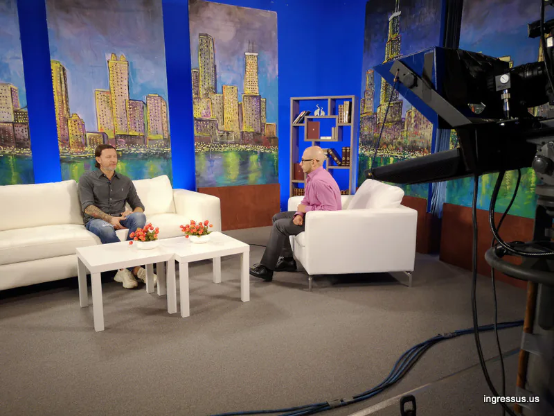 Television interview on a studio set with a painted Chicago skyline, ahead of the Soccer Legends Cup match