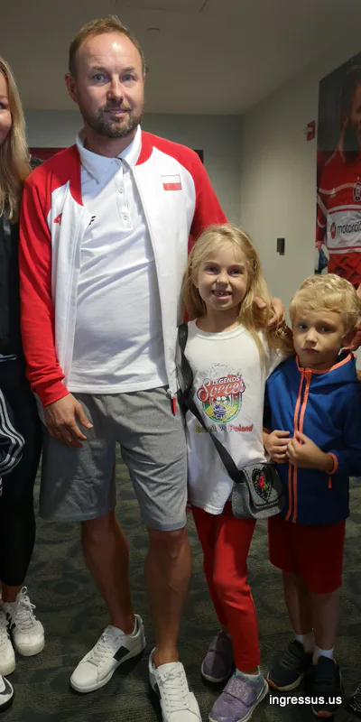 Man in a Poland team tracksuit with two children, one in a Soccer Legends Cup T-shirt, inside the stadium