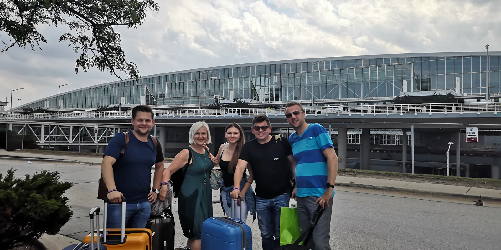 Five travelers with suitcases outside an airport terminal, heading home after the Polonaise Festival trip to Chicago, August 2019