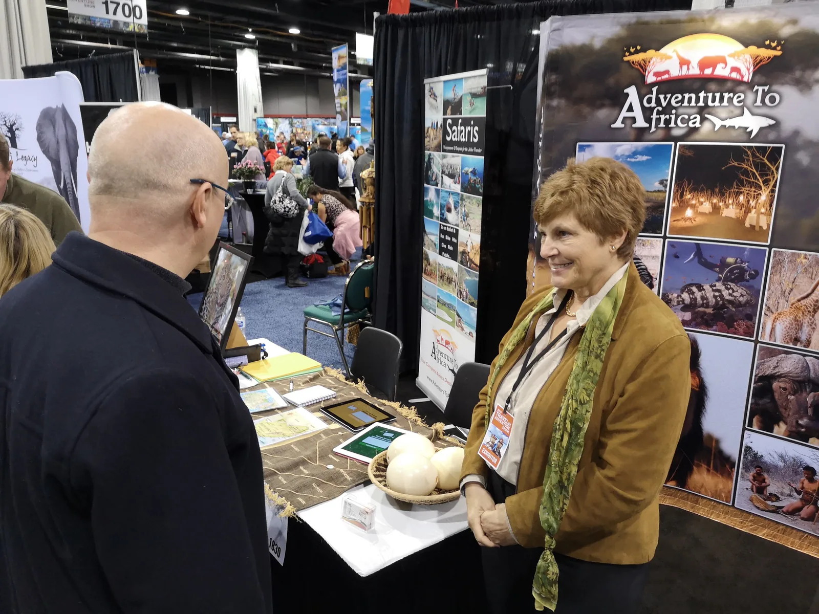 Exhibitor at the Adventure To Africa safari booth talking with a visitor at the Chicago Travel & Adventure Show 2019 in Rosemont