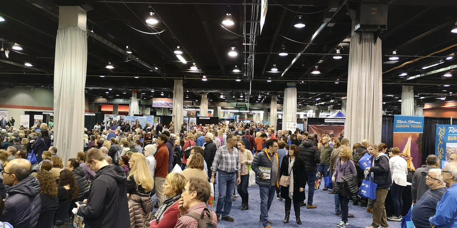 Wide view of the crowded exhibition floor with a Rick Steves Europe Tours booth at the Chicago Travel & Adventure Show 2019