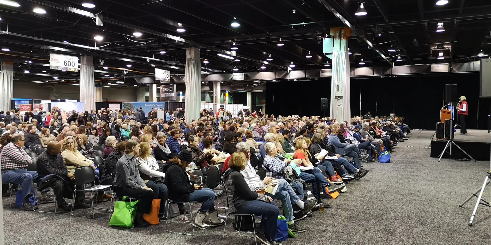 Large audience seated in rows listening to a speaker at a podium at the Chicago Travel & Adventure Show 2019 in Rosemont