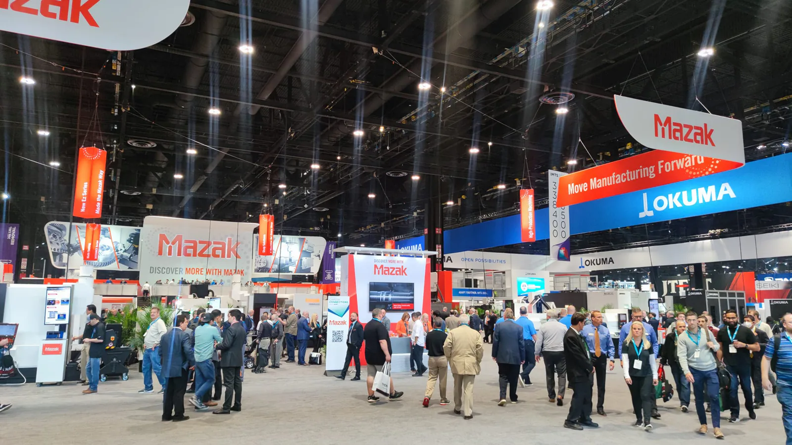 Visitors walking through the IMTS 2022 show floor past large Mazak and Okuma exhibits