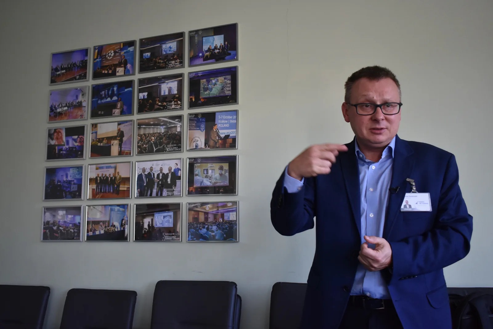 Jarosław Stankowski, director of St. Luke's Hospital in Bielsko-Biała, talking to the journalists in front of a wall of conference photos