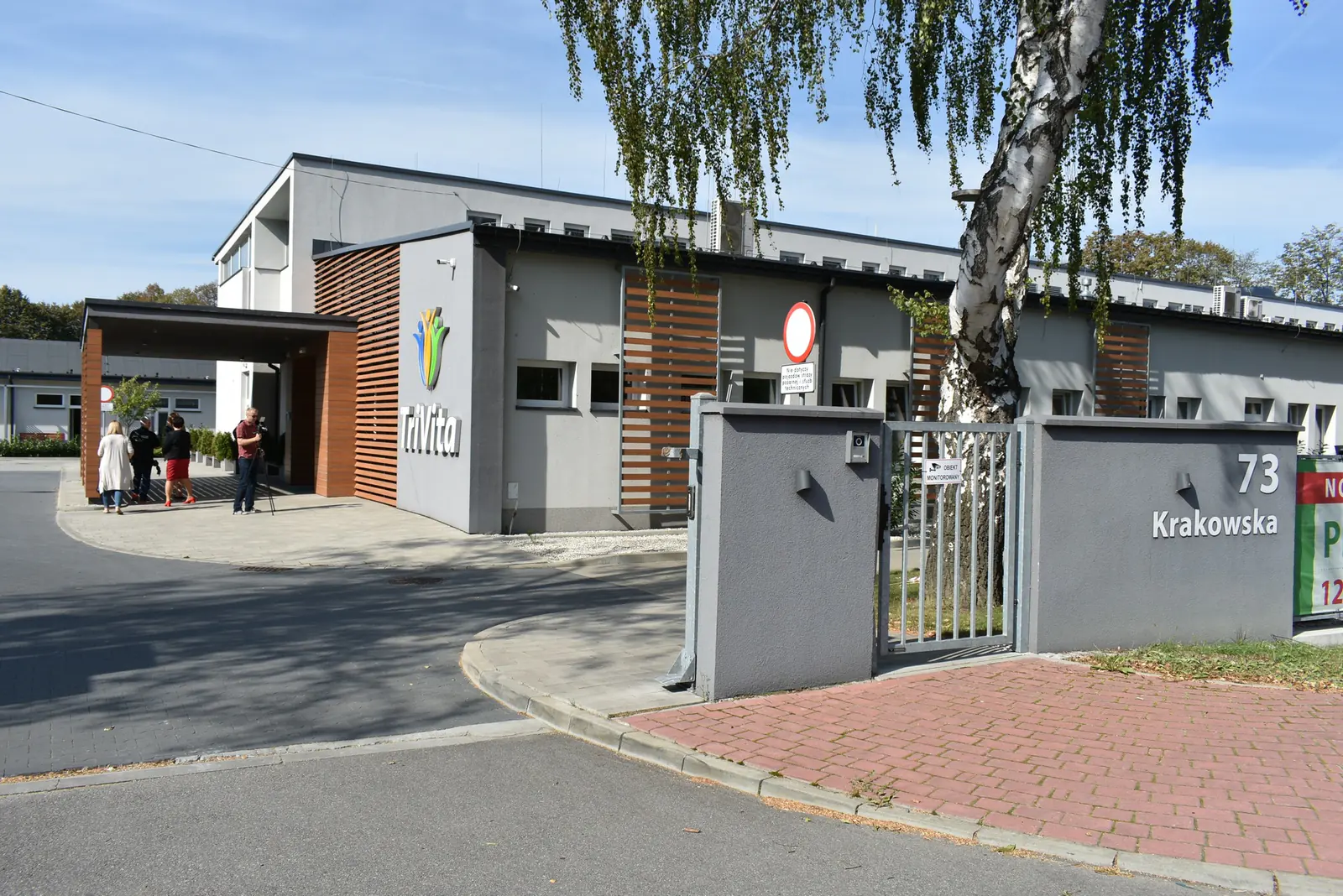 TriVita Center for Modern Rehabilitation and Care at 73 Krakowska Street in Porąbka, with a camera crew at the entrance
