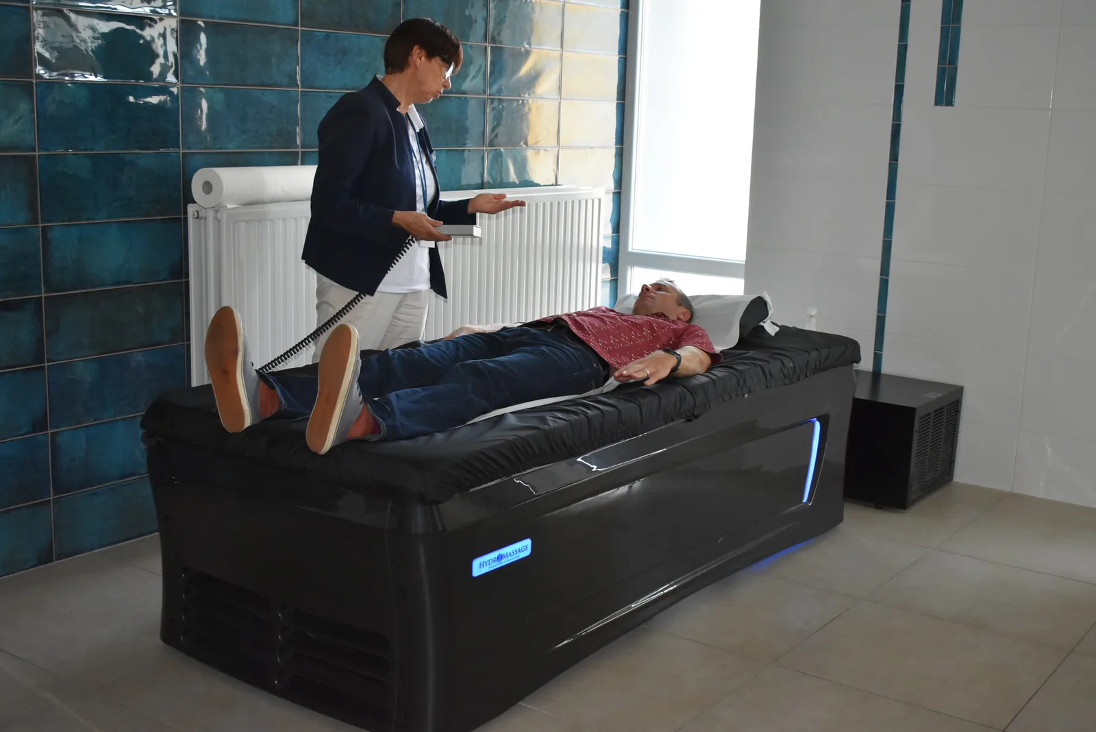 Staff member showing a hydromassage bed to a visitor in a treatment room at the TriVita center in Porąbka