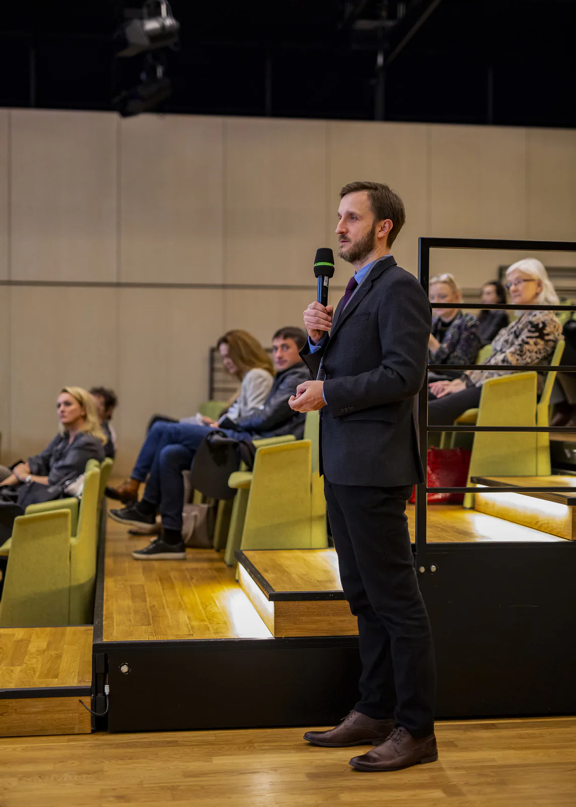 Participant standing with a microphone in the auditorium during a question and answer session