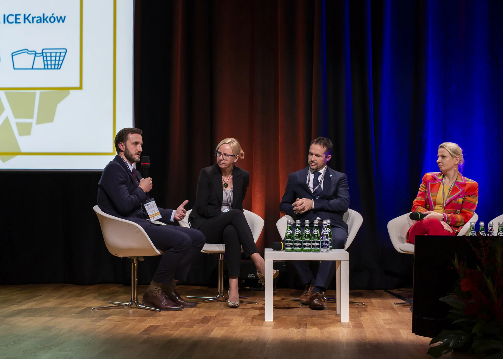 Four panelists on stage, one speaking into a microphone, during a session of the Kraków medical tourism congress