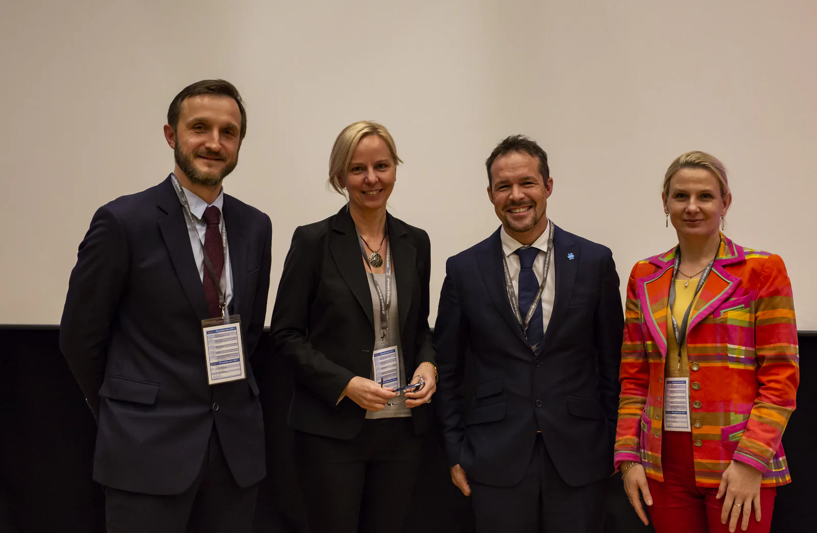 Four congress panelists with name badges smiling for a photo after their session
