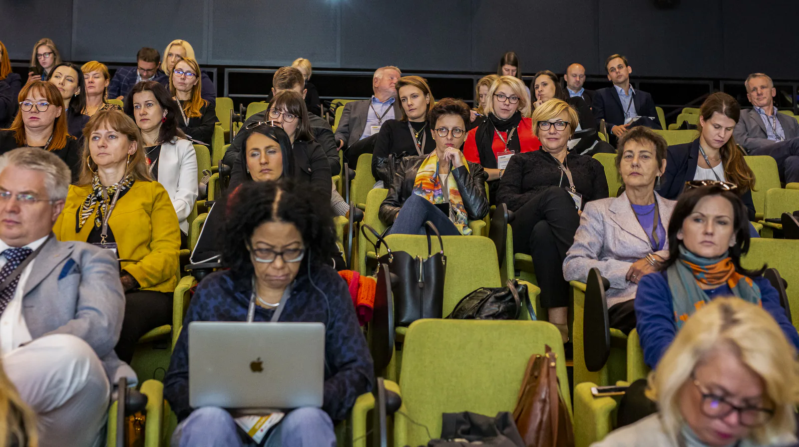 Full rows of medical tourism congress participants in the auditorium, one taking notes on a laptop
