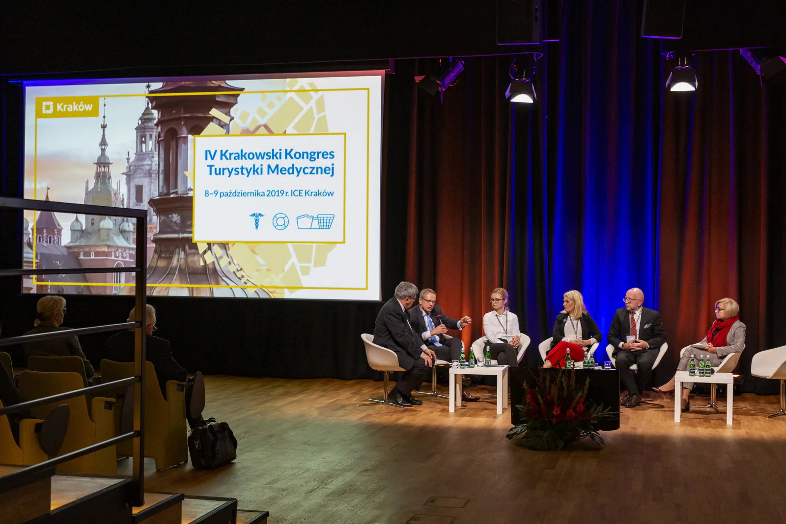 Wide view of the ICE Kraków stage with six panelists seated beneath the 4th Kraków Medical Tourism Congress title screen
