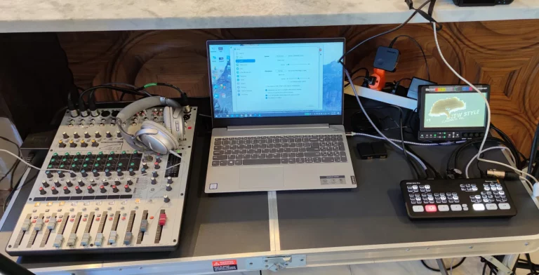 Live streaming production setup with an audio mixer and headphones, a laptop, a field monitor and an ATEM Mini Pro video switcher