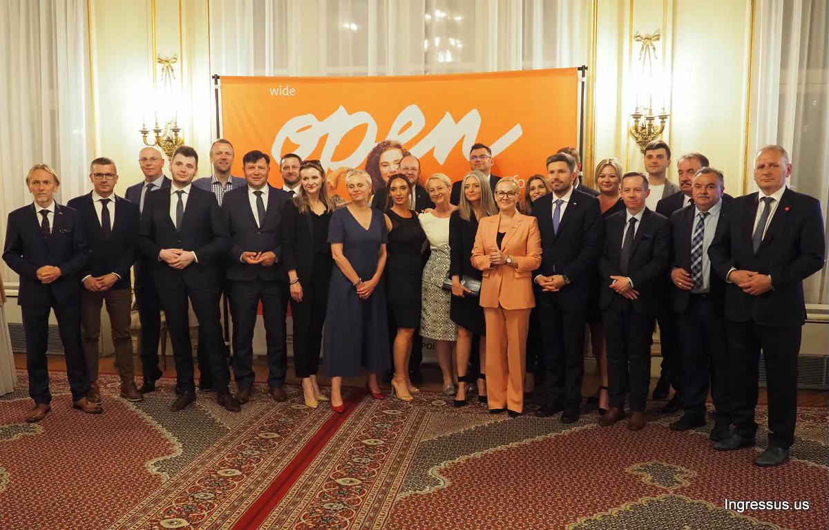 Małopolska region delegation and guests posing together in front of an orange Open for food banner in an ornate hall in New York