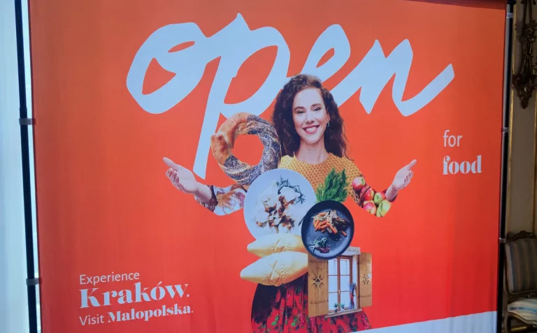 Experience Kraków, Visit Małopolska banner with the slogan Open for food and a woman holding regional dishes, from the delegation's New York visit