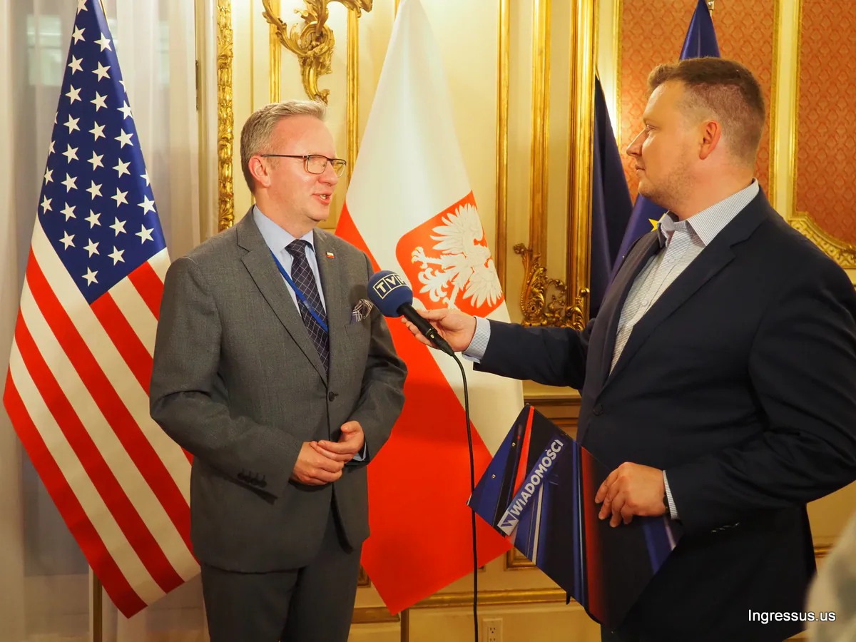 TVP reporter interviewing a guest in front of U.S. and Polish flags during the Małopolska presentation in Manhattan