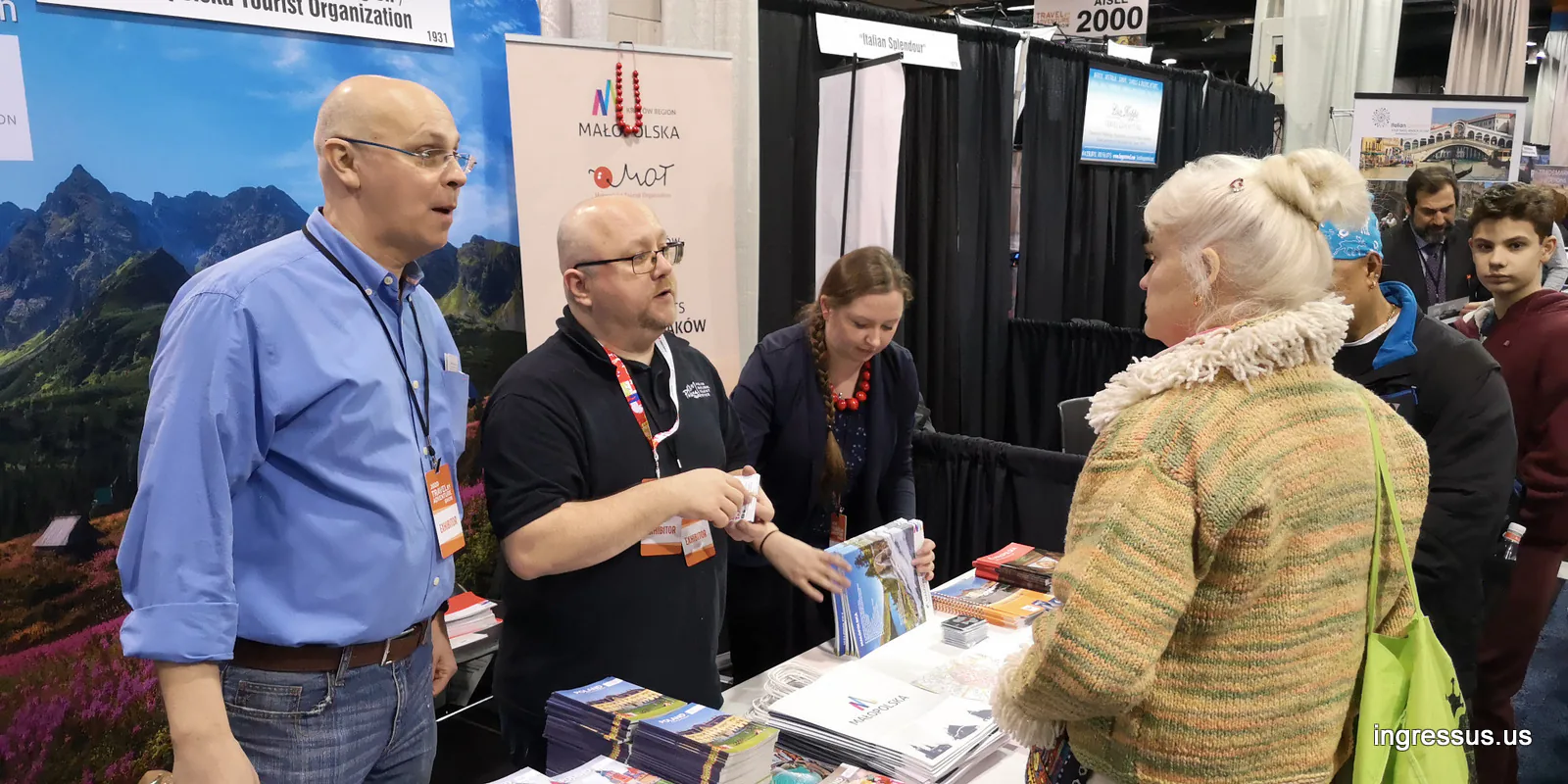 Exhibitors at the Małopolska Tourist Organization booth handing out travel brochures to visitors at the 2020 Travel & Adventure Show