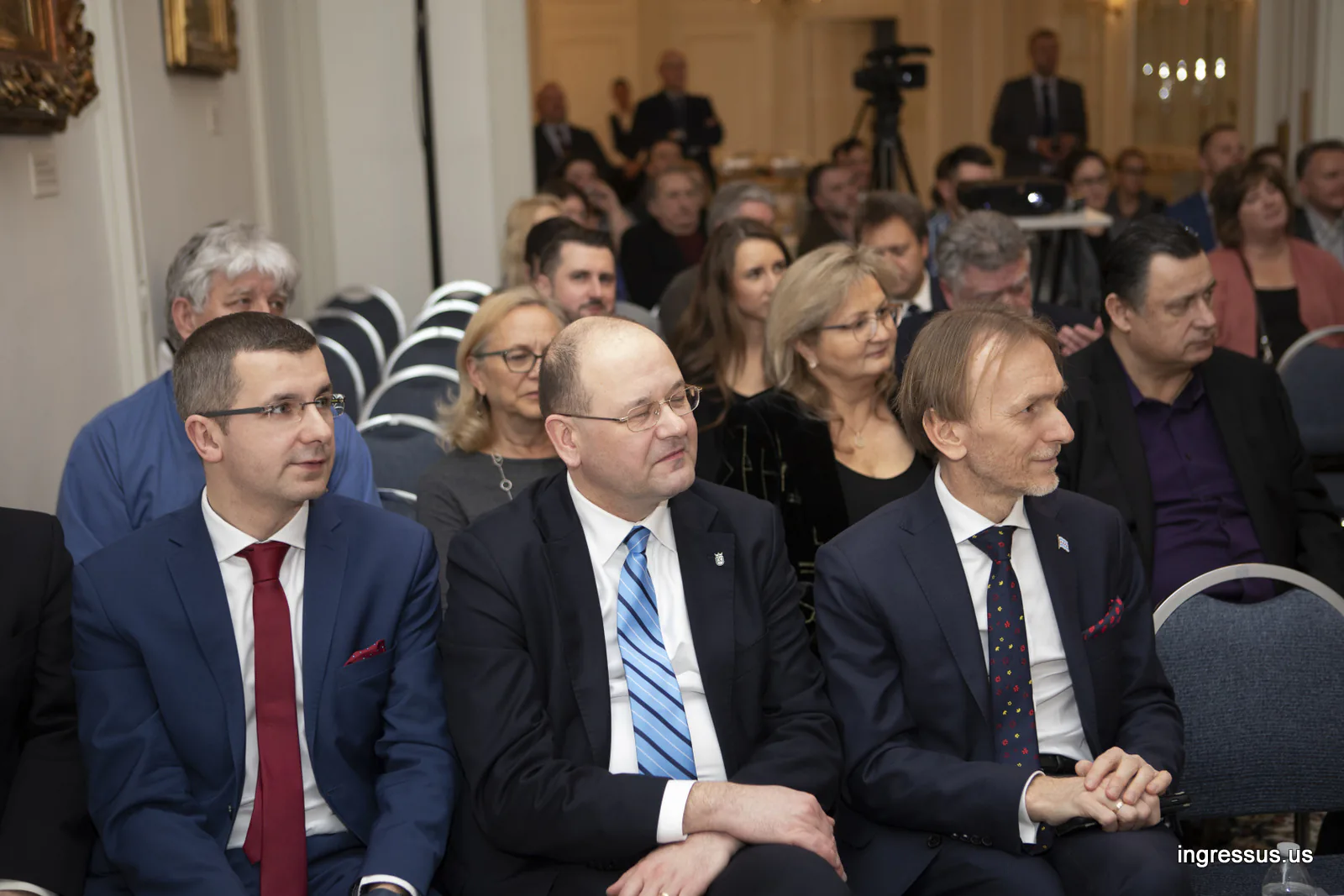 Guests in the front rows following the presentation, with a video camera behind them, at the Polish Consulate General in Chicago