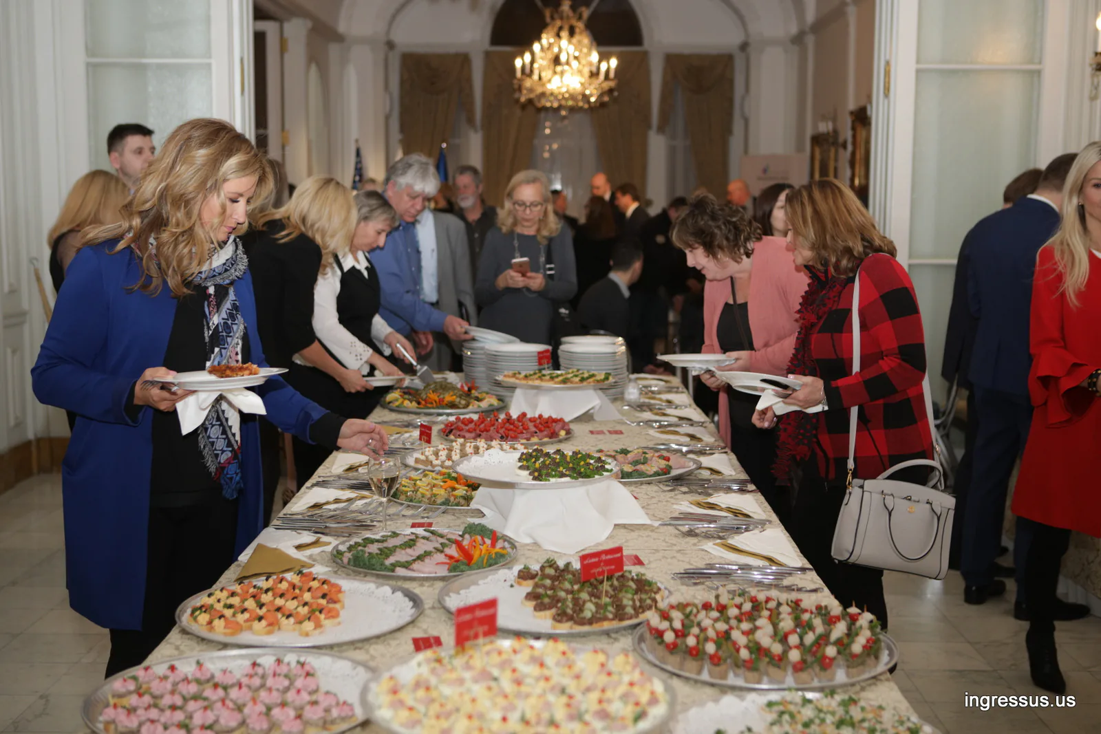 Guests serving themselves from the canapé buffet under a chandelier at the Polish Consulate General in Chicago