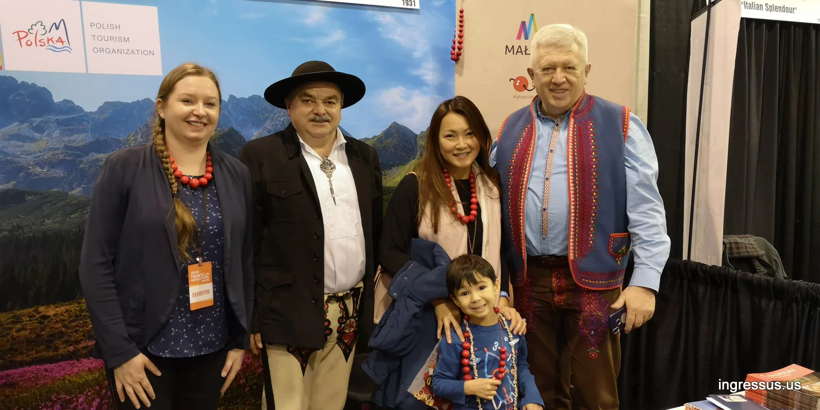 Guests in Polish highlander outfits and red coral necklaces posing with an exhibitor at the Polish Tourism Organization booth