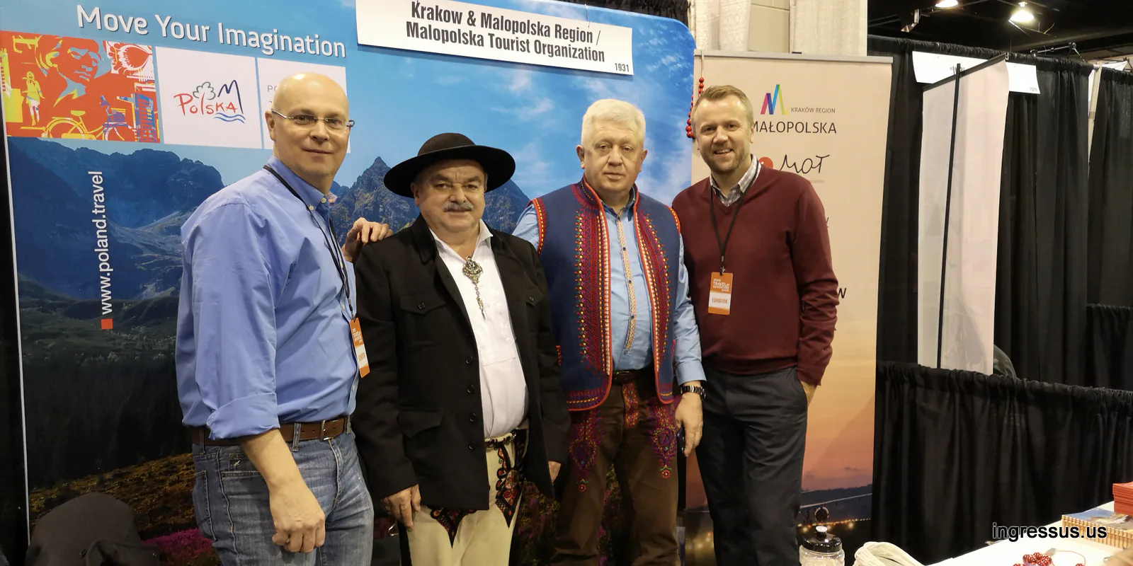 Four men, two of them in Polish highlander outfits, at the Kraków and Małopolska Region booth with Polish Tourism Organization banners