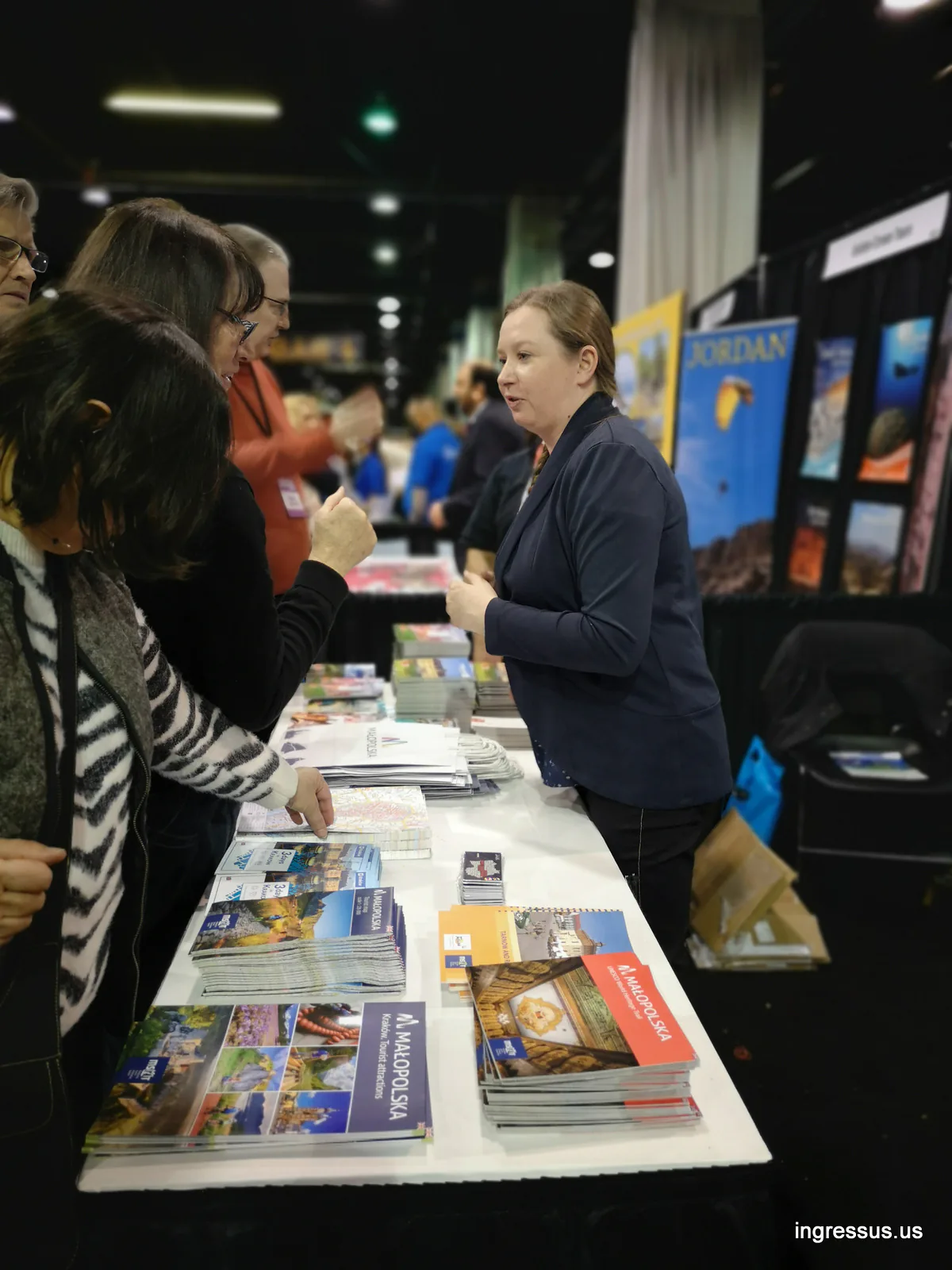Exhibitor at the Małopolska booth showing Kraków travel guides and brochures to visitors at the Travel & Adventure Show