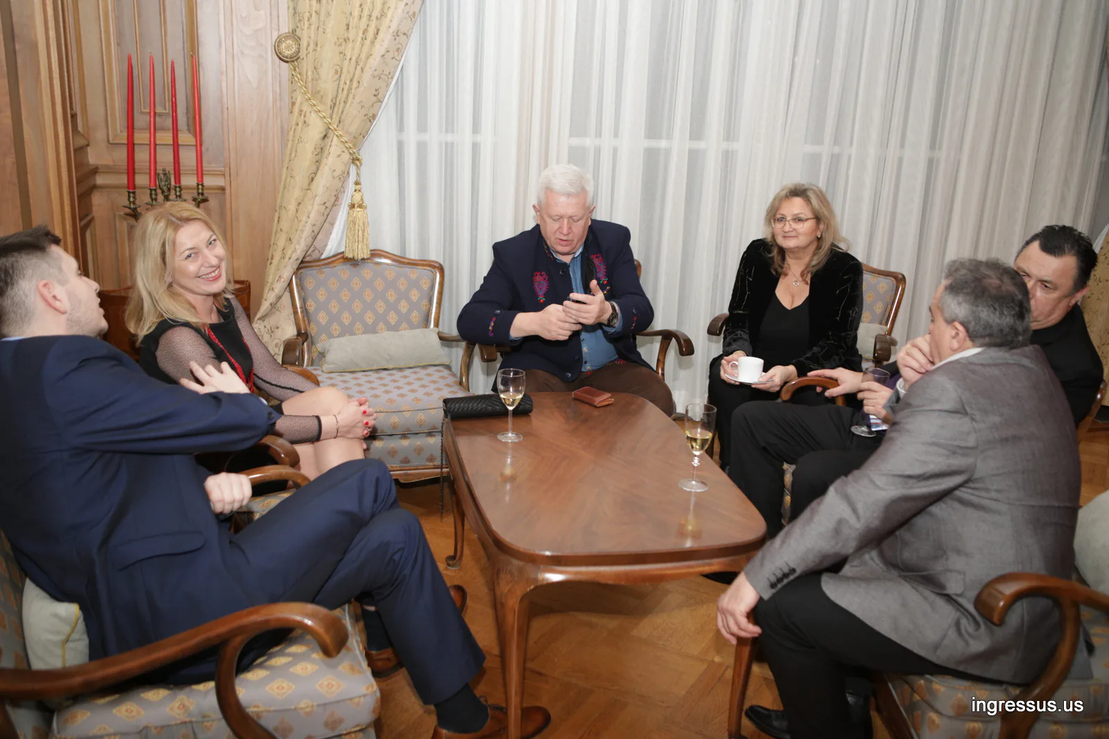 Guests talking in armchairs around a coffee table in a wood-paneled salon at the Polish Consulate General in Chicago