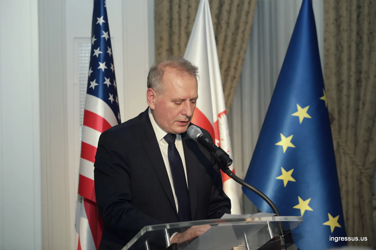 Speaker at a podium in front of U.S., Polish and European Union flags during the event at the Polish Consulate General in Chicago
