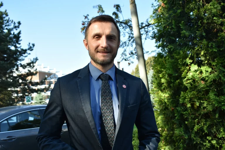 Mariusz Arent, adviser to the Polish Tourism Organization on promoting Polish health services, smiling outdoors in a suit