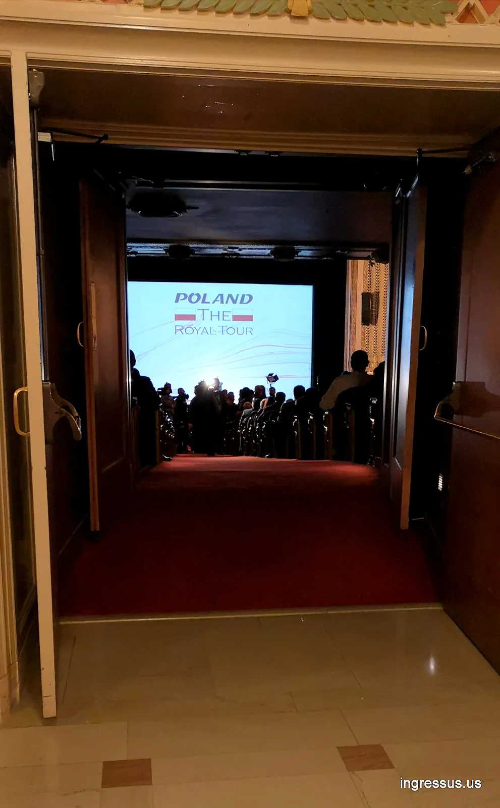 Open doors leading into the Lyric Opera House auditorium, with the Poland: The Royal Tour title on the screen ahead