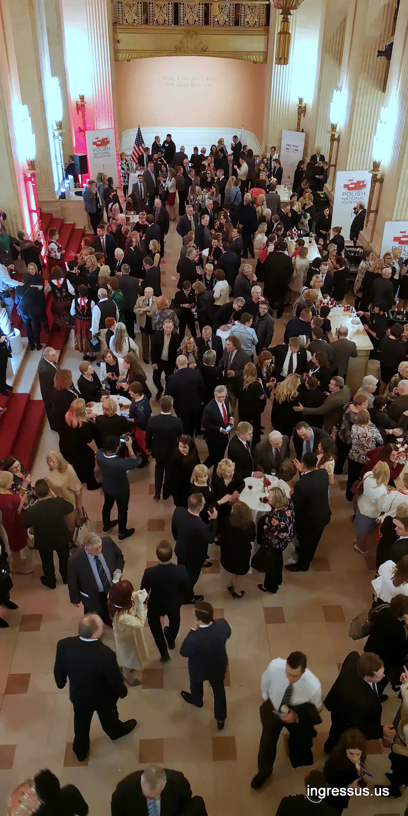 Crowd of premiere guests in the Lyric Opera House foyer with Polish National Foundation banners, seen from the balcony