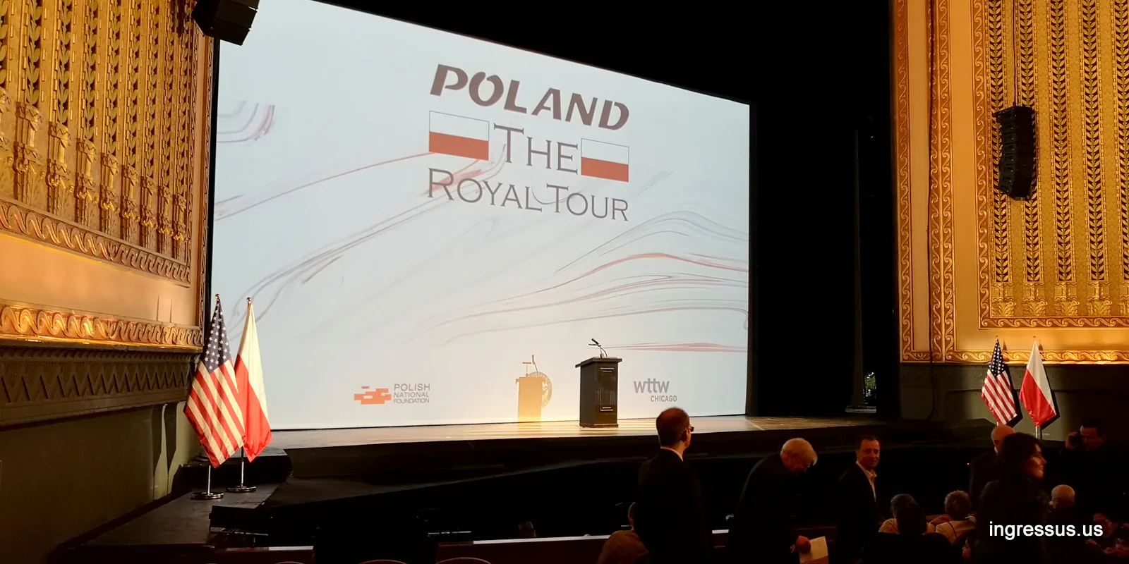 Stage of the Lyric Opera House with the Poland: The Royal Tour title screen, a podium and US and Polish flags, Chicago