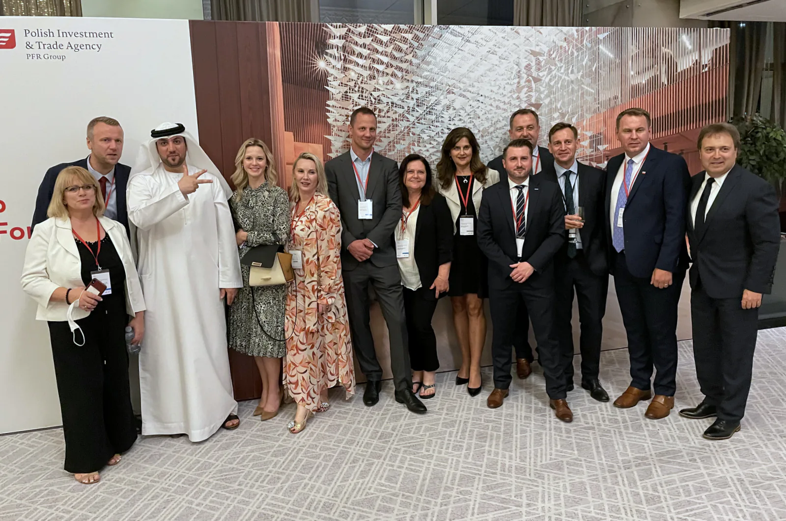 Trade mission group with an Emirati guest in front of a Polish Investment and Trade Agency backdrop in Dubai