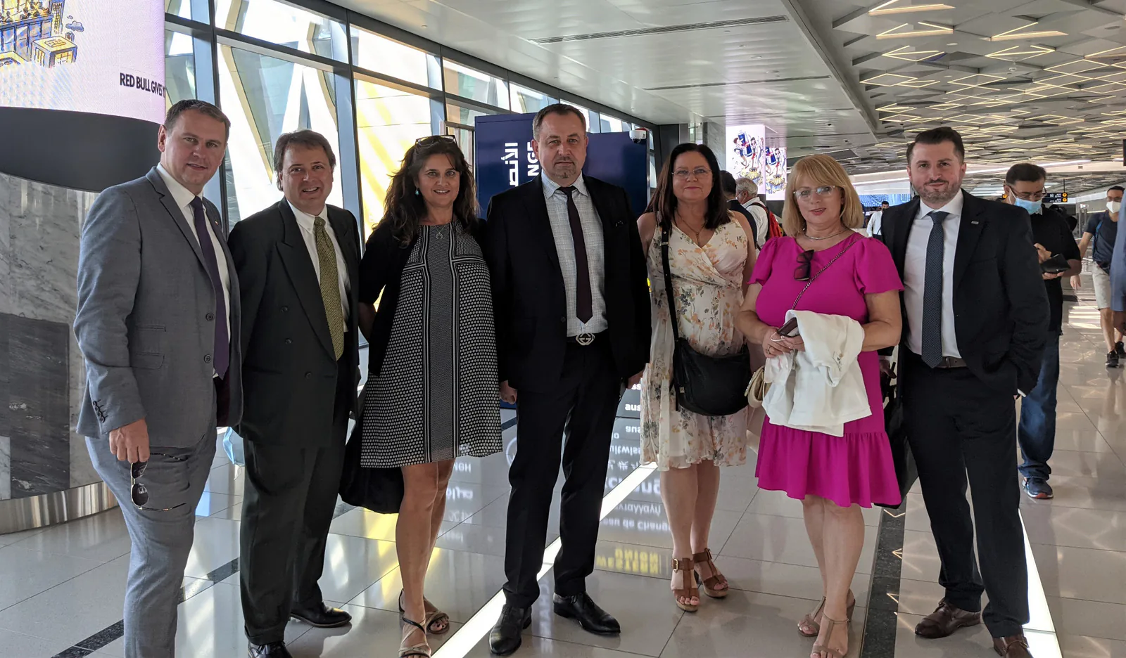 Seven trade mission participants posing together in a bright, modern transit hall in Dubai