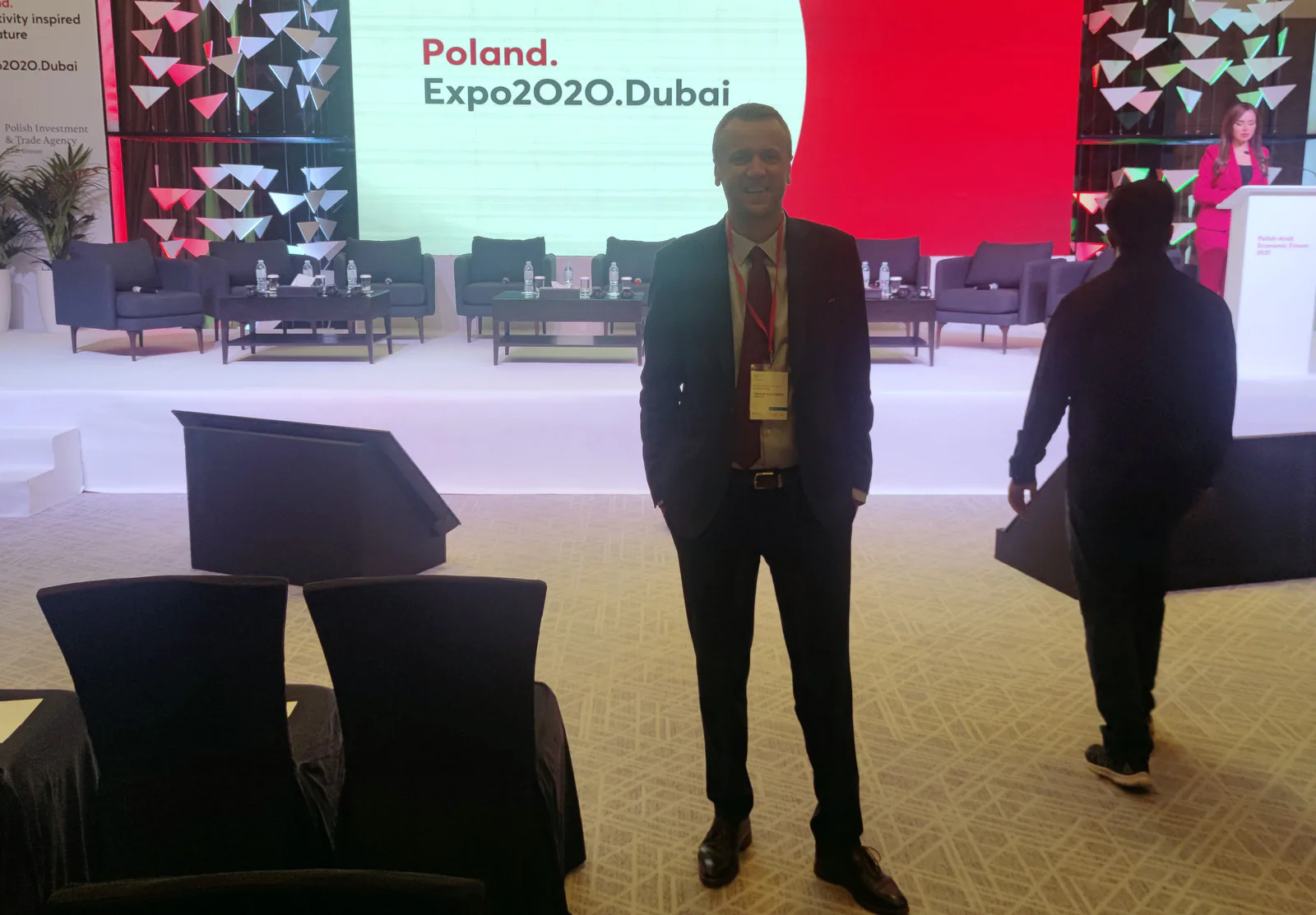 Participant with a conference badge standing in front of the Poland Expo2020 Dubai stage before a forum session
