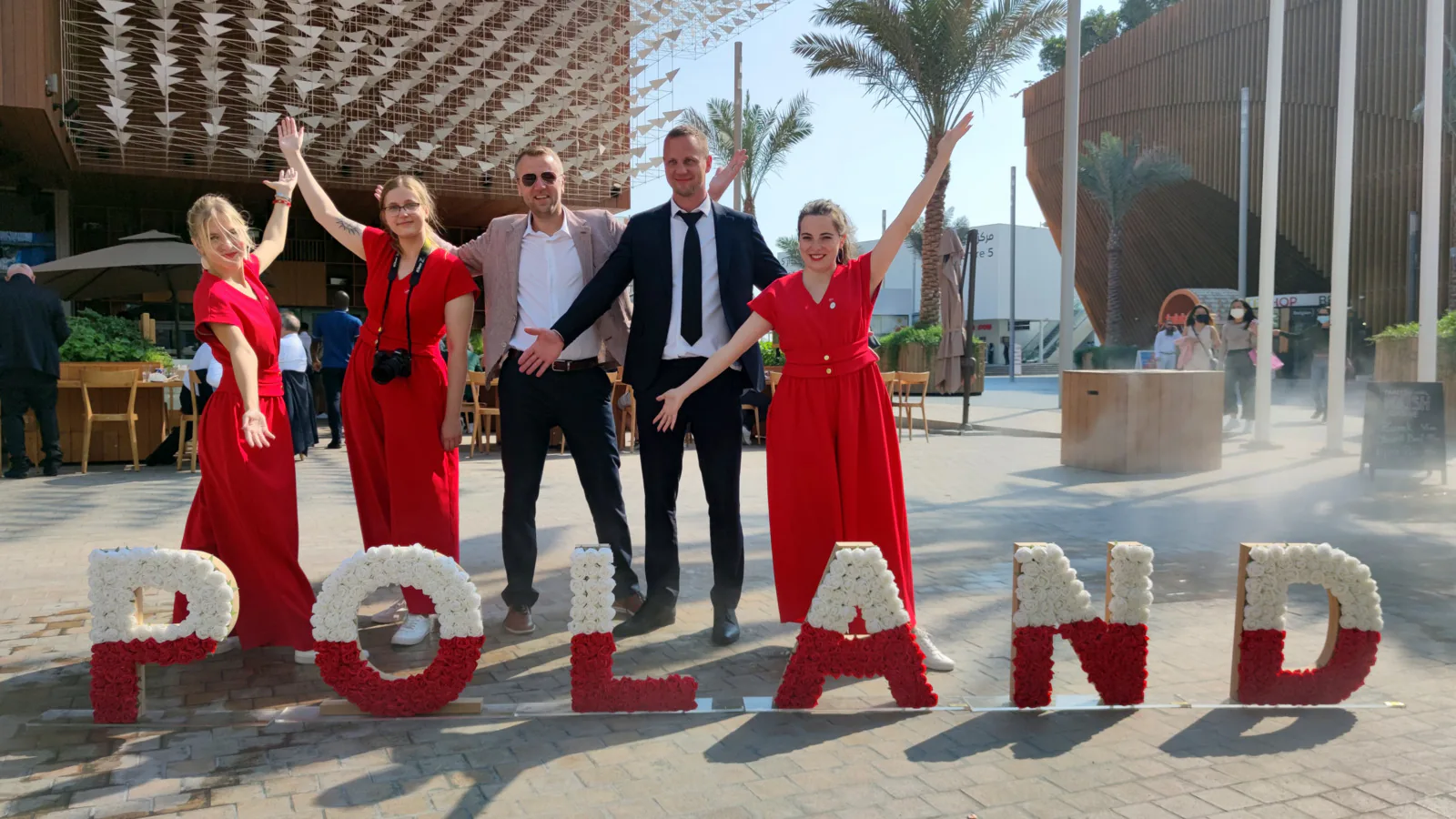 Trade mission participants posing behind large POLAND letters made of red and white flowers at Expo 2020 Dubai